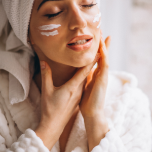 Woman applying facial cream in a cozy spa robe