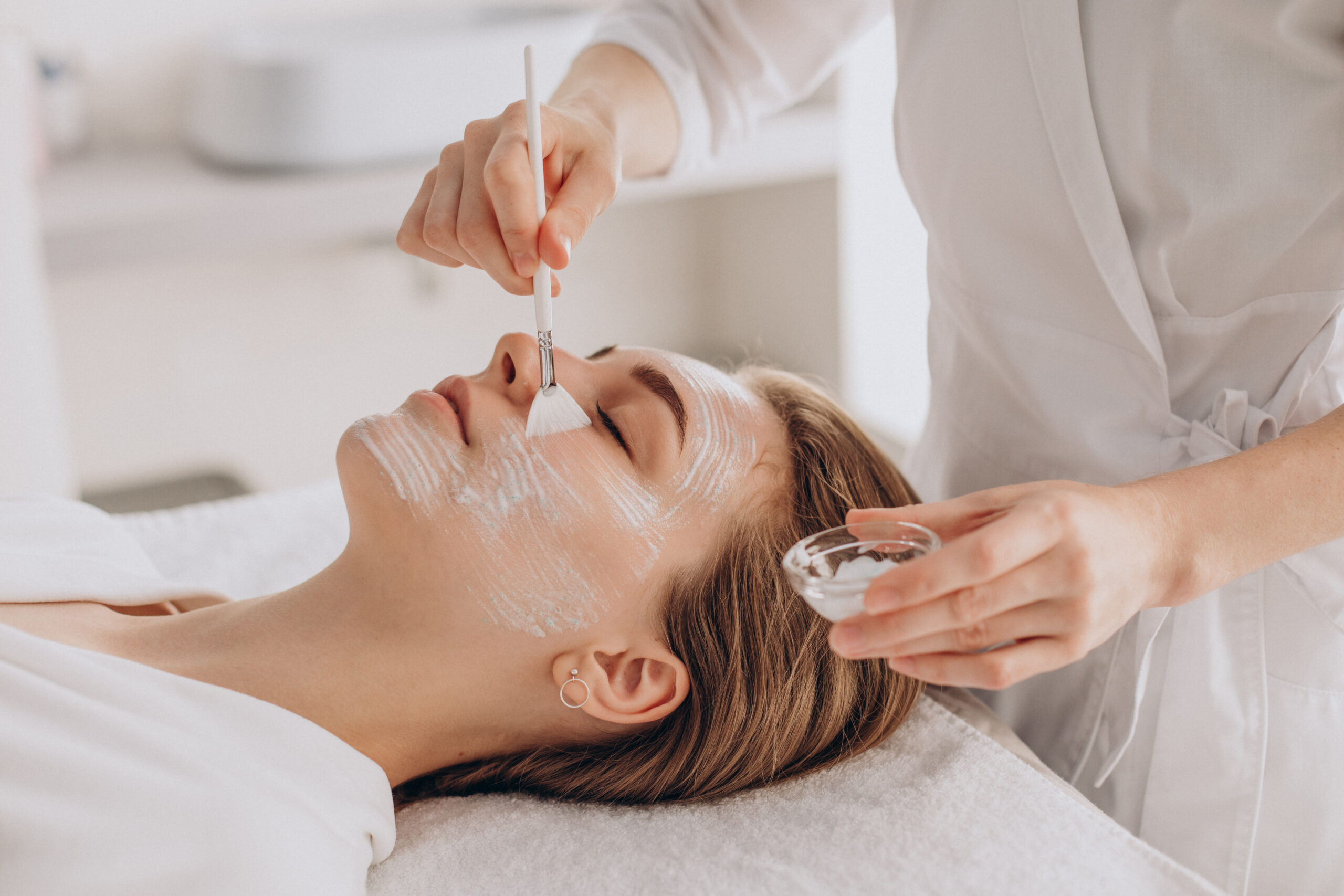 Relaxing facial treatment with a spa professional applying a mask to a client's face.